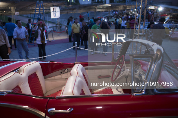 An Iranian woman is taking photographs of an American car, a 1957 Ford Skyliner, during a classic car and motorcycle show in northern Tehran... by Morteza Nikoubazl/NurPhoto