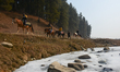 Tourists are riding horses beside a partially frozen stream in Gulmarg, a ski destination,...