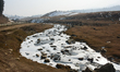 A partially frozen stream is flowing in Gulmarg, a ski destination, on a dry winter day in...