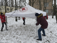 Volunteers from a rapid response unit of the Ukrainian Red Cross Society are setting up a tent to provide help for people evacuated from a f...
