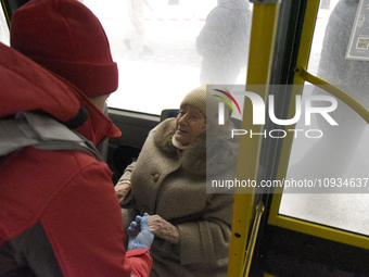 In Kyiv, Ukraine, on January 23, 2024, a senior woman is receiving help to board a bus as she waits for permission to return to her five-sto...