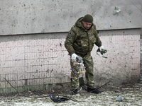 A serviceman is picking up Russian missile debris outside an apartment building in the Sviatoshynskyi district after the Russian missile att...