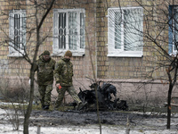 Two servicemen are examining the premises outside an apartment building in the Sviatoshynskyi district after the Russian missile attack on T...