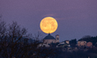 Wolf moon sets behind dome and bell tower of San Bernardino church in L'Aquila, Italy, on...