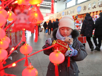 A child is buying Spring Festival ornaments at a small commodity market in Lianyungang, China, on January 27, 2024. (