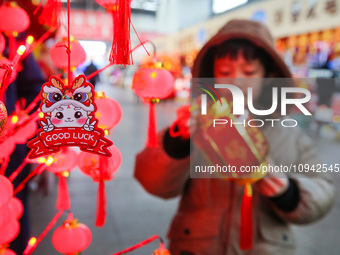 A child is buying Spring Festival ornaments at a small commodity market in Lianyungang, China, on January 27, 2024. (