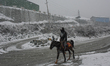 A man is riding a horse amid heavy snowfall in the Gagangir area of Ganderbal district, 70...