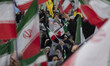 A veiled Iranian woman is holding a poster featuring portraits of Iran's Supreme Leader Ay...