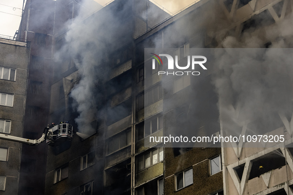 Firefighters are working at the site of a burning residential high-rise building that was damaged by a massive Russian missile strike in Kyi...