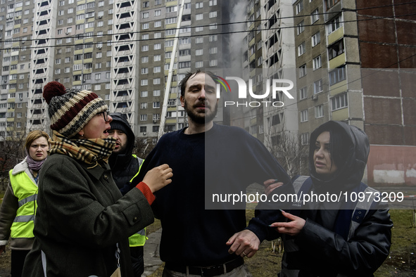 Local residents are reacting next to a burning residential high-rise building that has been damaged by a massive Russian missile strike in K...
