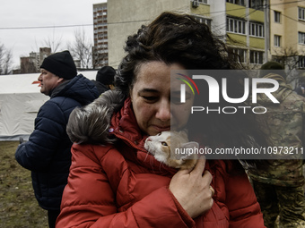 A local woman with a cat is reacting next to a burning residential high-rise building damaged by a massive Russian missile strike in Kyiv, U...