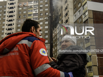 A rescuer is helping a woman from a burning residential high-rise building that has been damaged by a massive Russian missile strike in Kyiv...