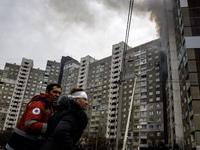 A rescuer is helping a woman from a burning residential high-rise building that has been damaged by a massive Russian missile strike in Kyiv...