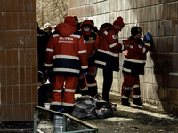Medical workers are inspecting the bodies of victims found in a burning residential high-rise building damaged by a massive Russian missile...