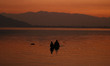 Men are steering a boat on the waters of Dal Lake during sunset in Srinagar, India, on Feb...