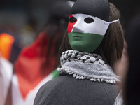 A protester wearing a Palestinian face mask is participating as hundreds of people join a pro-Palestine march against Israel's attacks on Ga...