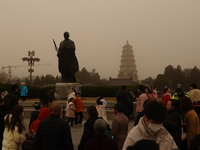 Tourists are wearing masks as they visit the Dayan Pagoda scenic spot during a dusty day in Xi'an, China, on February 18, 2024. It is unders...