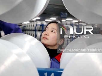 A worker is checking the quality of finished silk at a workshop of a chemical fiber company in Suqian, China, on February 18, 2024. (