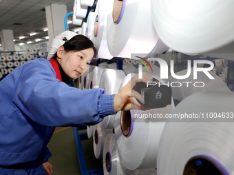 A worker is checking the quality of finished silk at a workshop of a chemical fiber company in Suqian, China, on February 18, 2024. (