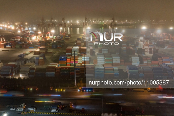 Vehicles are carrying containers to and from the Qianwan Container Terminal of Qingdao Port under heavy fog in Qingdao, China, on the evenin...