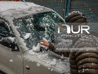 A man is clearing snow from his car in Baramulla, Jammu and Kashmir, India, on February 20, 2024. (