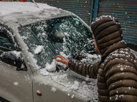 A man is clearing snow from his car in Baramulla, Jammu and Kashmir, India, on February 20, 2024. (