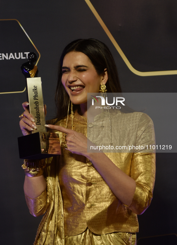 Bollywood actress Karishma Tanna is posing for a photoshoot while holding an award in her hand during a red carpet event of the 'Dadasaheb P...