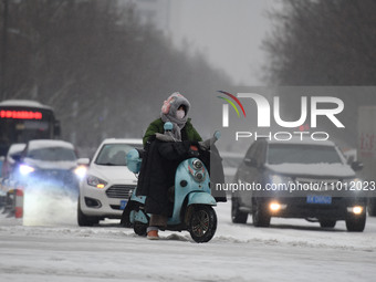 Citizens are riding in the snow on a street in Fuyang, China, on February 21, 2024. (