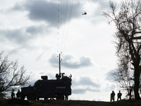 Gendarmes Mobiles are standing guard near a Centaure, an armored vehicle, while a police helicopter is flying nearby at the 'Crem'Arbre' ZAD...