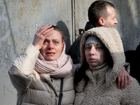 Residents are standing near a block of flats that was hit by a Russian Shahed drone during an overnight attack in Dnipro, Ukraine, on Februa...