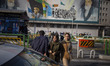 Two young Iranian women are walking under a mural featuring portraits of Iran's Supreme Le...