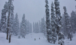 A man is walking with a sledge amid heavy snowfall at a ski resort in Gulmarg, Baramulla D...