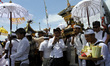 Hindu devotees are carrying offerings as they pray during the Melasti ritual ceremony at P...