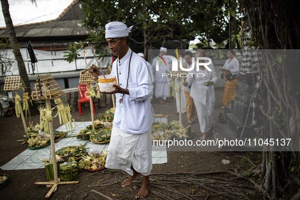 An Indonesian Hindu priest is pouring holy water during a cleansing ceremony called 'Melasti' at Segara Temple in Jakarta, Indonesia, on Mar...