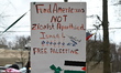 A pro-Palestinian protester is holding up a sign that reads, ''Fund Americans not Zionist...