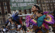 A woman performing a pre-Hispanic dance is carrying her daughter in the Zocalo of Mexico C...
