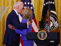 President Joe Biden is kissing his wife, First Lady Dr. Jill Biden, at an event celebrating Women's History Month at the White House in Wash...