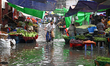 A vegetable vendor is waiting for customers in a waterlogged market at Karwan Bazar in Dha...