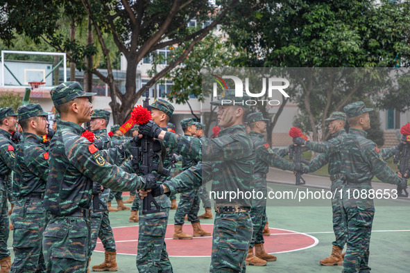 Newly joined SWAT team members are receiving weapons from veteran members during the 2024 SWAT team induction ceremony in Nanning, Guangxi P...