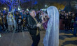 An Iranian man is dancing with a street artist dressed as a life-size doll in a park in do...