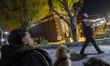 An Iranian man and his pets are sitting next to a scale model of the Kaaba in a park in do...