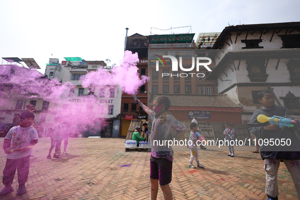 Children are setting off colored smoke while celebrating Holi, the festival of colors, at Kathmandu Durbar Square, a UNESCO World Heritage S...
