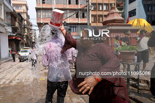 A Nepali reveler is splashing water on a fellow reveler while celebrating the festival of Holi, the festival of colors, in Kathmandu Durbar...