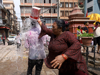 A Nepali reveler is splashing water on a fellow reveler while celebrating the festival of Holi, the festival of colors, in Kathmandu Durbar...