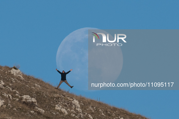 A man reaction in front of full worm moon is seen in L’Aquila, Italy, on march 23th, 2024. The Worm Moon is the traditional name for the ful...