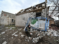 A law enforcement officer is standing next to a building damaged by Russian shelling in the frontline village of Prymorske, in Zaporizhzhia,...