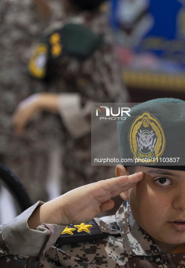 A young Iranian schoolboy in a military uniform is saluting while posing for a photograph in the Imam Khomeini Grand Mosque during the 31st...