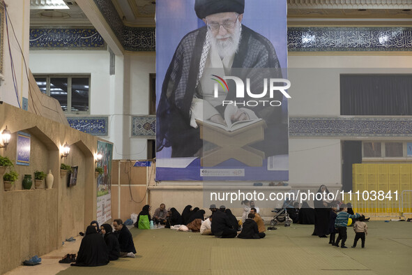 Iranian worshippers are resting under a massive portrait of Iran's Supreme Leader, Ayatollah Ali Khamenei, in the Imam Khomeini Grand Mosque...