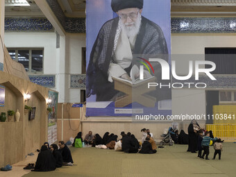 Iranian worshippers are resting under a massive portrait of Iran's Supreme Leader, Ayatollah Ali Khamenei, in the Imam Khomeini Grand Mosque...
