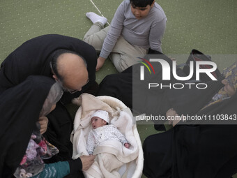 An Iranian family is sitting around a newborn baby in the Imam Khomeini Grand Mosque, attending the 31st edition of the International Holy Q...